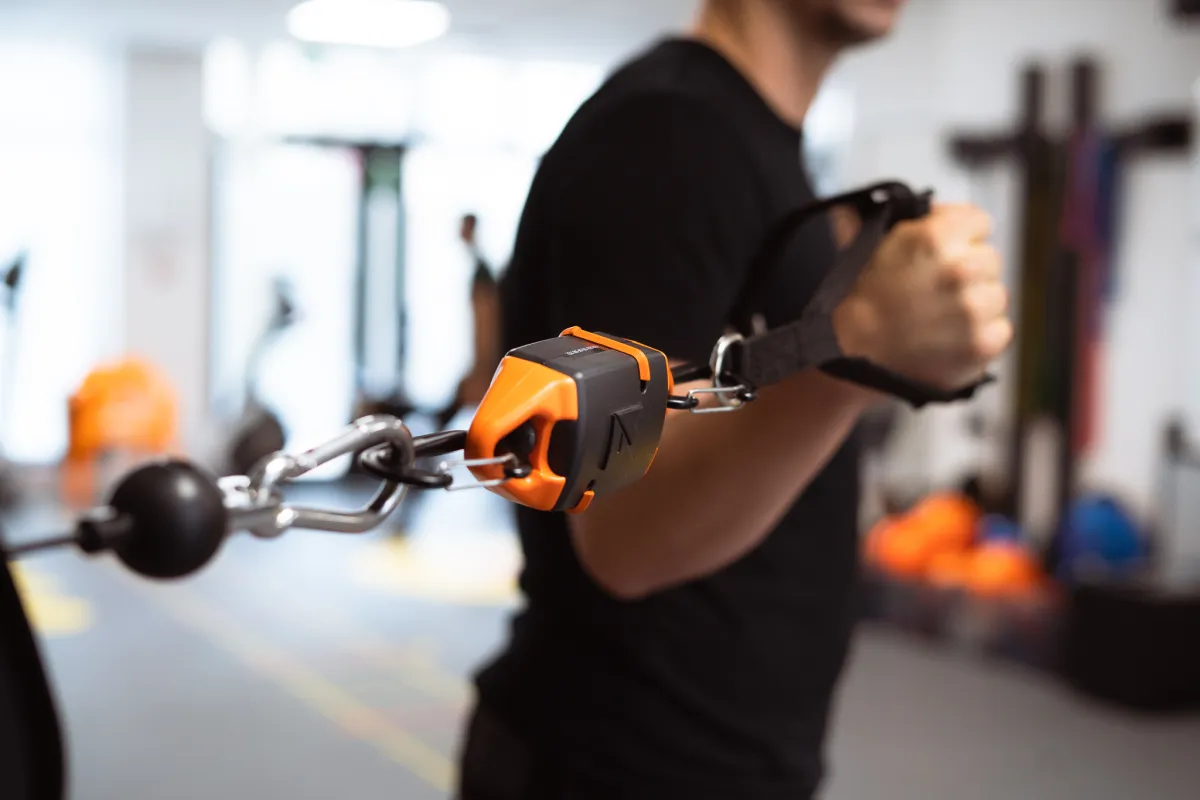 Adhérent tirant sur un câble de poulie, la sangle de poignet reliée par un module orange