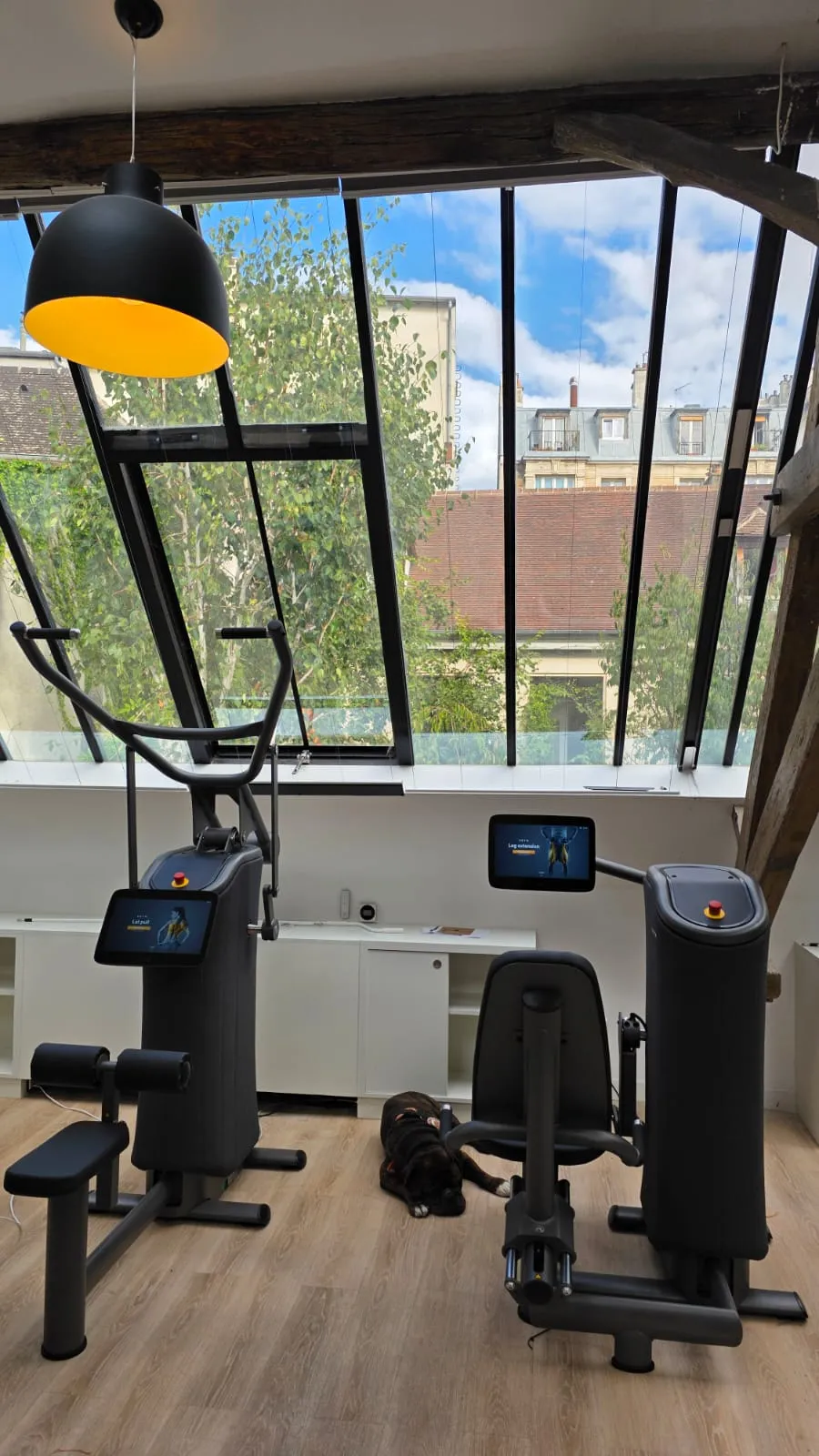 Deux machines eGym à écran sous la verrière et les poutres du site Paris Marais