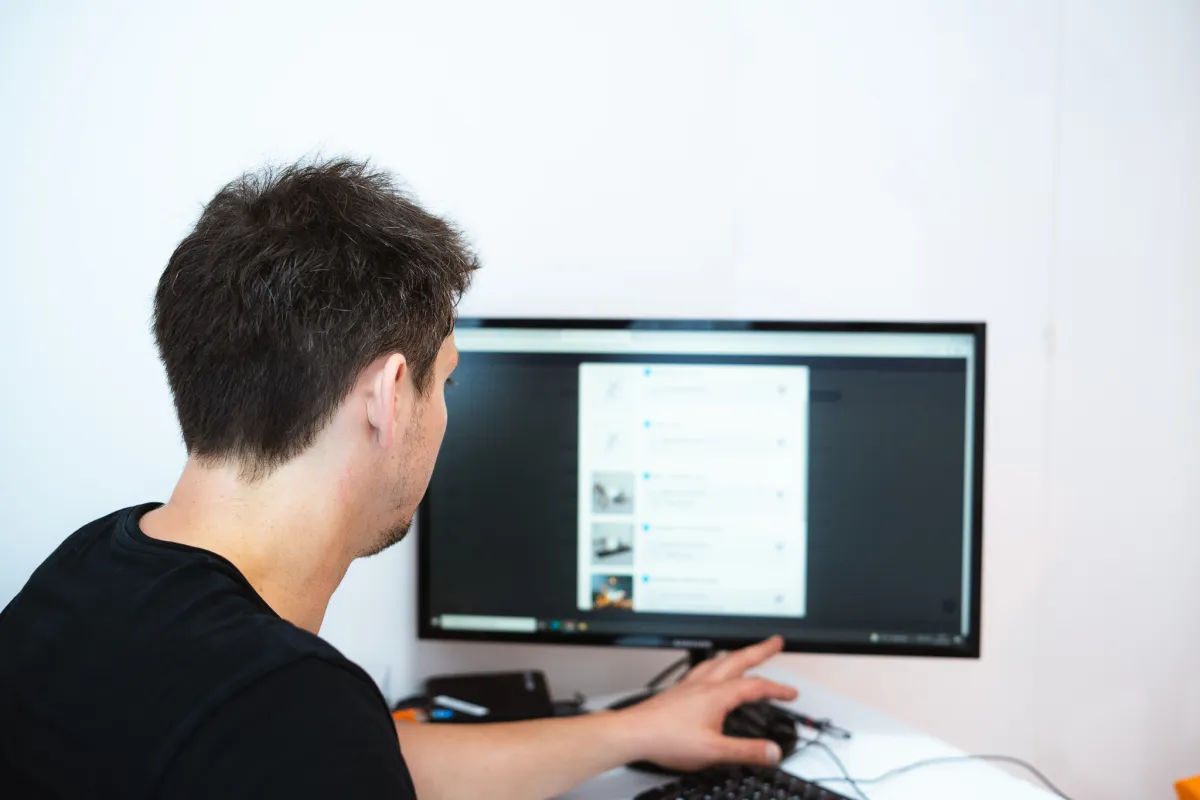 Homme de dos consultant un programme d'entraînement affiché sur un écran d'ordinateur